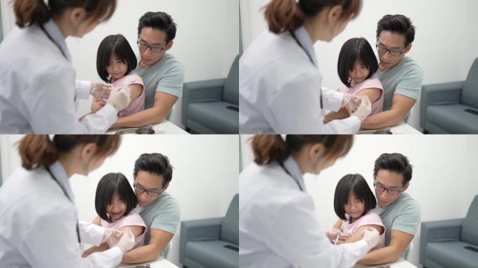 亚裔中国女医生在诊所给孩子打针。注射期间，小女孩大喊大叫。她的父亲帮助照顾他的女儿。
