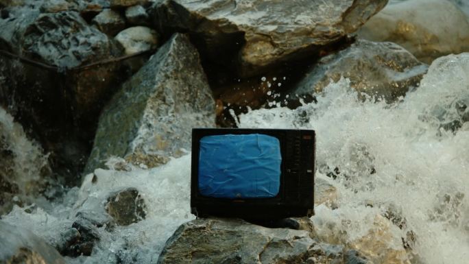 蓝幕扣像河道中石头上的电视机