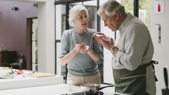 一对年长的夫妇在家里的厨房里做饭。一个成熟的男人和女人一起吃健康的饭，享受轻松的退休生活