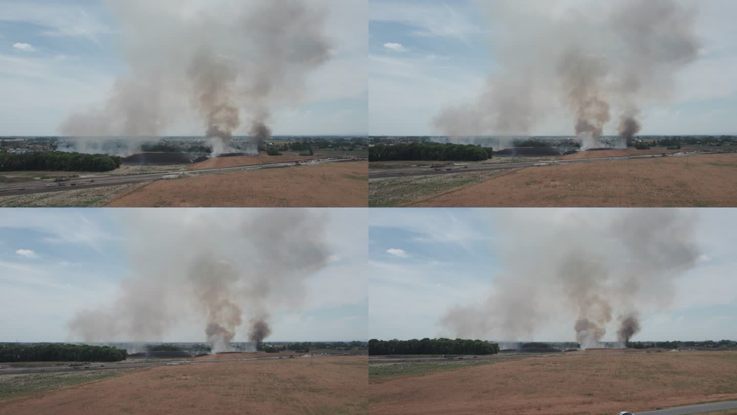 农田起火。鸟瞰图。从直升机上看，从远处看。相机向后起飞。棕灰色烟雾。直升机着陆。
