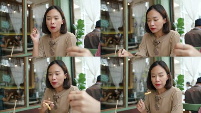 年轻的亚洲女性在当地餐厅吃午饭时与朋友谈论一天。