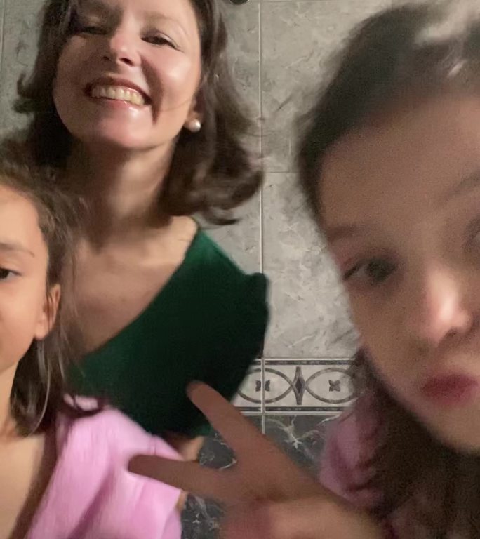 母亲和女孩在家里的浴室里用手机跳舞和拍摄-手机摄像头视角