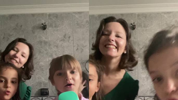 母亲和女孩在家里的浴室里用手机跳舞和拍摄-手机摄像头视角