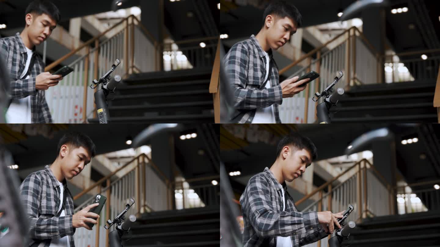 亚洲男子手持智能手机解锁电动滑板车。