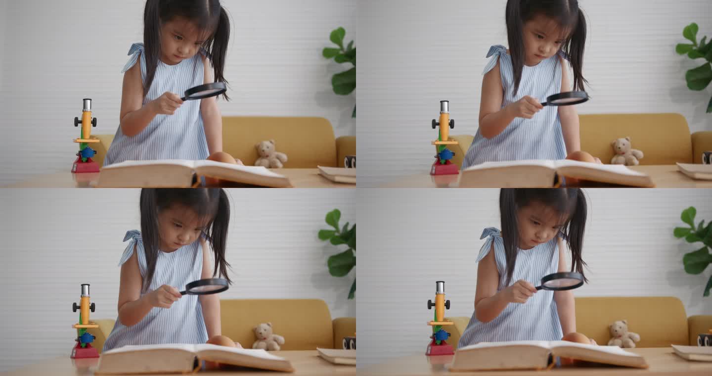 年轻的亚洲女孩在客厅里读带放大镜的书