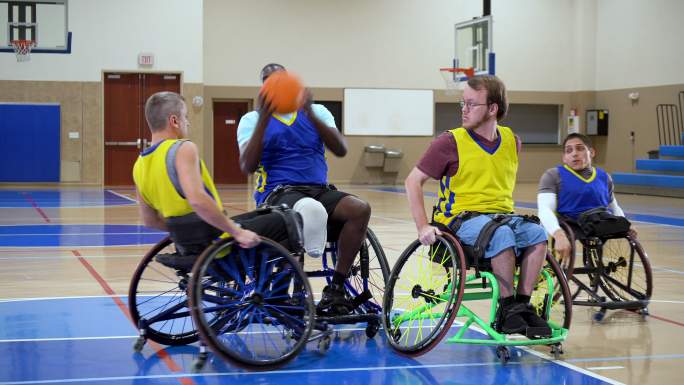四名男子在轮椅上打篮球、传球和运球