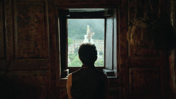 藏族男子看窗外的佛塔