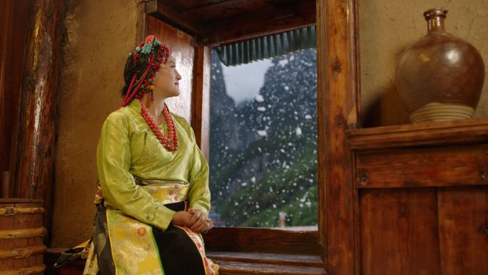 藏族女子坐在窗台赏雪