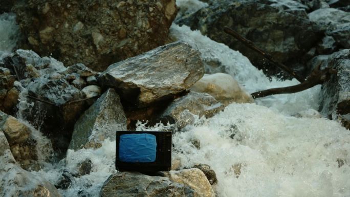 蓝幕扣像河道中石头上的电视机