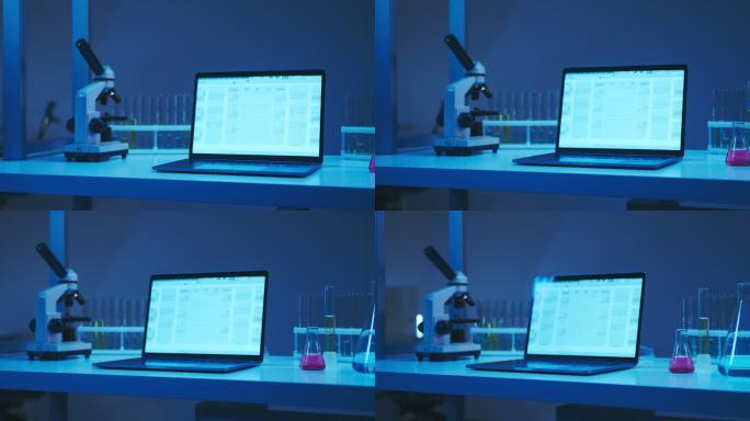 现代化实验室中的工作场所，配有笔记本电脑、显微镜和实验室烧瓶