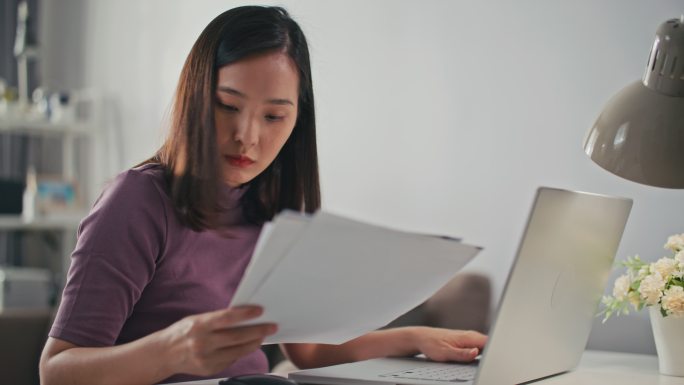 亚洲女性在家里用笔记本电脑在线支付账单