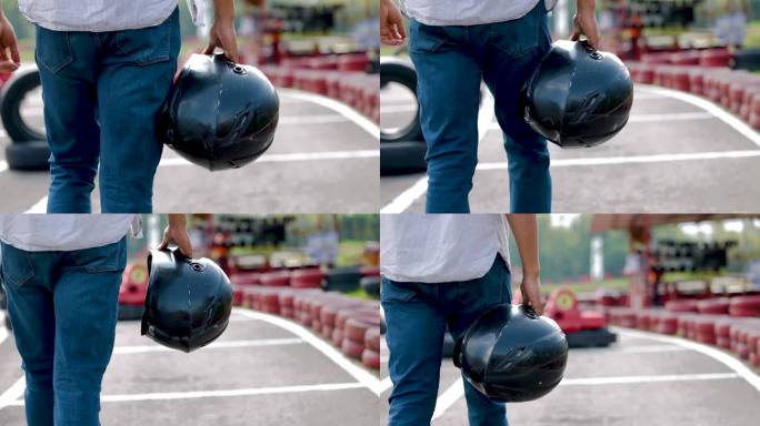 无法辨认的男子背着运动头盔在跑道上走向手推车的背影
