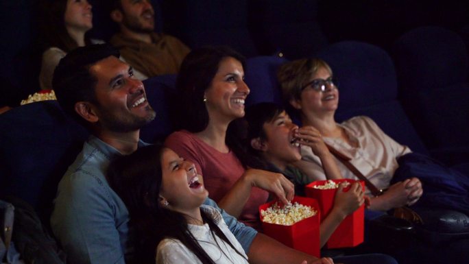 一家人在电影院看有趣的电影，同时享受爆米花和苏打水