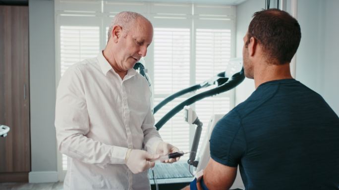 一名医生在运动诊所对一名男子运动员进行类固醇血液药物测试。医学专家提取血液样本，用于检测和分析医院内