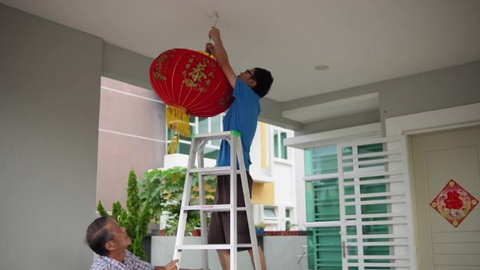 除夕夜，亚裔中国父亲在家前院给儿子递红灯笼