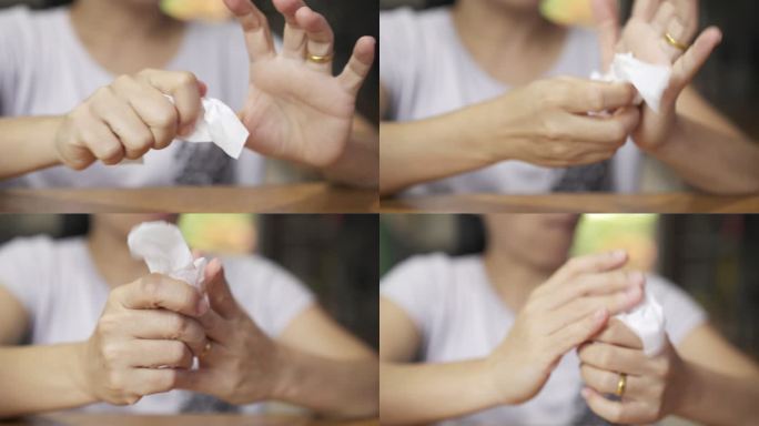 一位亚洲妇女在家里用纸巾擦脏手