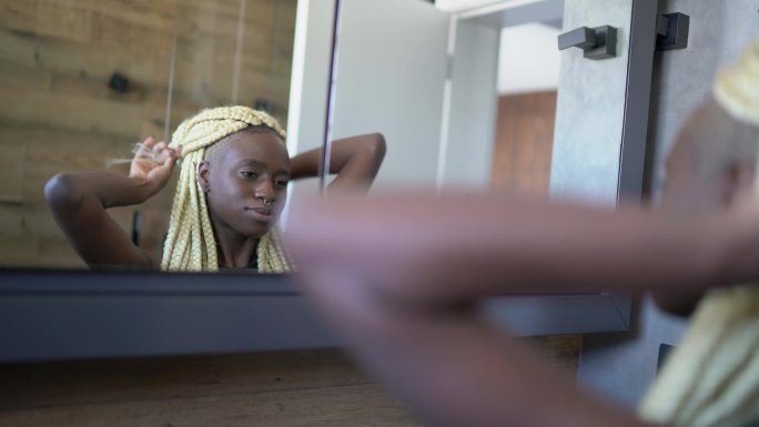 快乐的年轻女子看着镜子整理头发