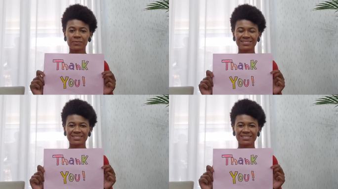 在视频通话中展示写有“谢谢”的纸的女人-网络摄像头视角