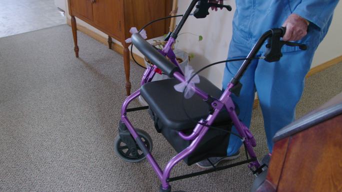 一名独立老年妇女推着一辆机动步行车穿过她家的手持式照片