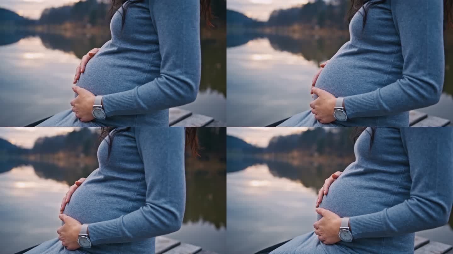 坐在码头上抚摸腹部的孕妇中部