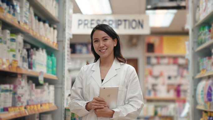 一位亚洲中国女药剂师站在她的零售店前看着镜头微笑