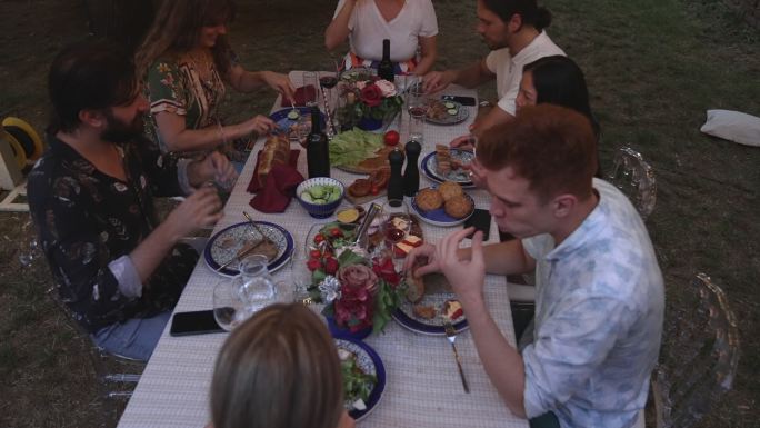 年轻人在后院吃晚饭，享受陪伴