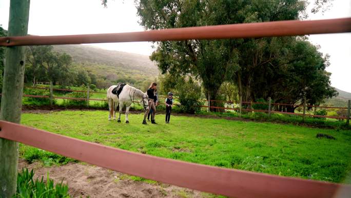 女教练和女孩在草地围场上骑着白马