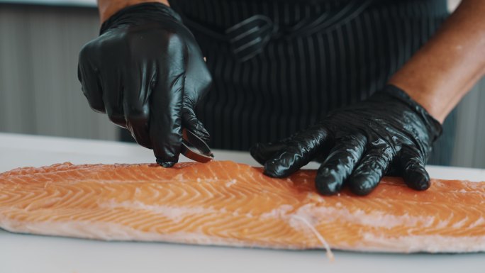 日本厨师正在从鲑鱼中取出鱼刺。