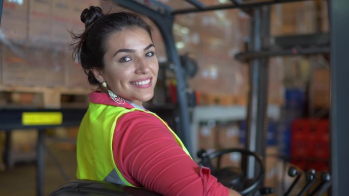 一名穿着防护服驾驶叉车的女性仓库工人的肖像