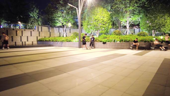 夜晚公园广场玩滑板车的年轻人