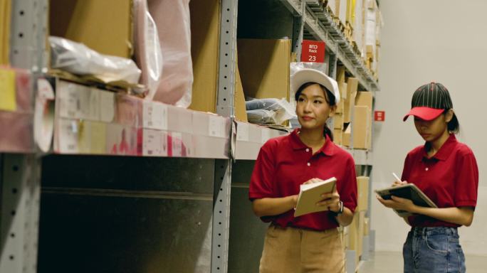 两名亚洲女性仓库工人使用平板电脑检查货架上的货物。检查员检查货架上出售的家具产品盒。仓库管理系统。计