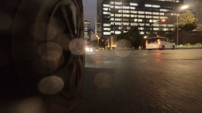 在雨夜驾车穿过城市。汽车车轮特写。在十字路口右转