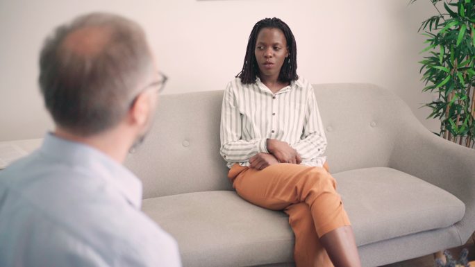 年轻的非裔美国女性与一位不知名的男性心理学家交谈