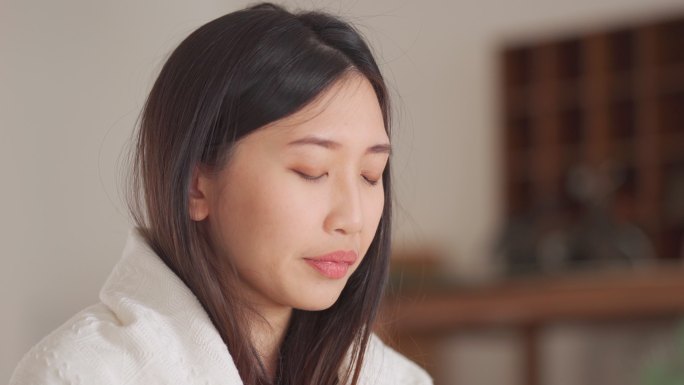 一位亚洲华裔女性，身上裹着毯子，正在服用日常避孕药组织者提供的感冒药和流感药 在家里