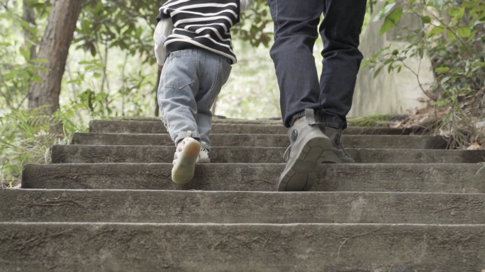 父子登山脚步特写爸爸牵着儿子登台阶背影