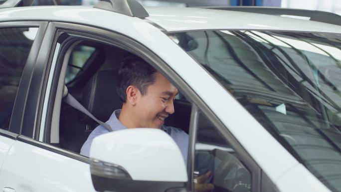 亚洲帅哥客户坐在车内时手持遥控车钥匙。帅气的男性客户在机械车库车间接受汽车服务、检查和维护汽车发动机