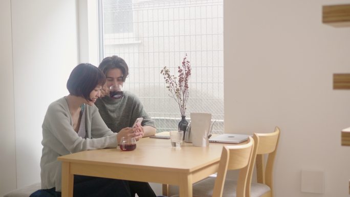 跨种族年轻夫妇一边喝咖啡一边使用智能手机