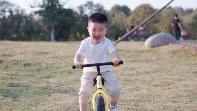 4K夕阳下一个可爱的小男孩在草坪骑平衡车