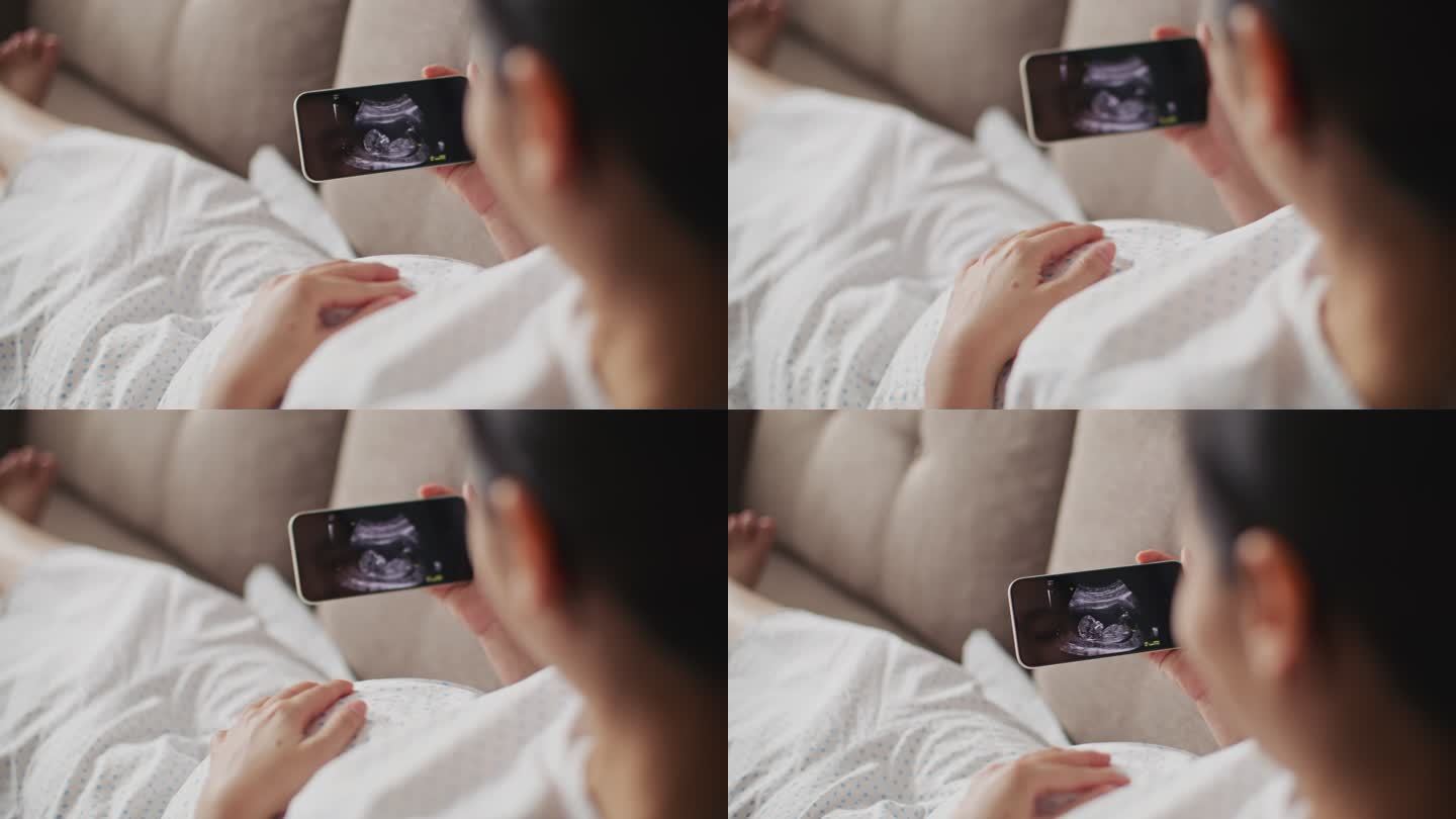孕妇坐在沙发上，看着手机上的超声波图像