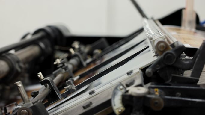一台自动化机器的特写镜头，将印刷媒体堆放在印刷厂