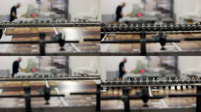 一台自动化机器的特写镜头，工人在后台工作时，将打印介质堆放在印刷厂