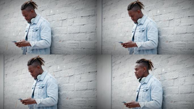 一个年轻人靠在灰色墙壁上使用智能手机的4k视频片段