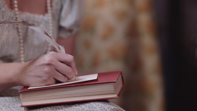女人穿着古装用羽毛笔写字。