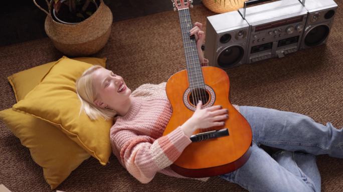 快乐的年轻女子在家弹吉他