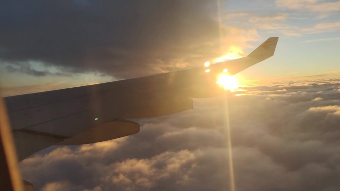 飞机窗户外穿越云层带机翼黄昏云层