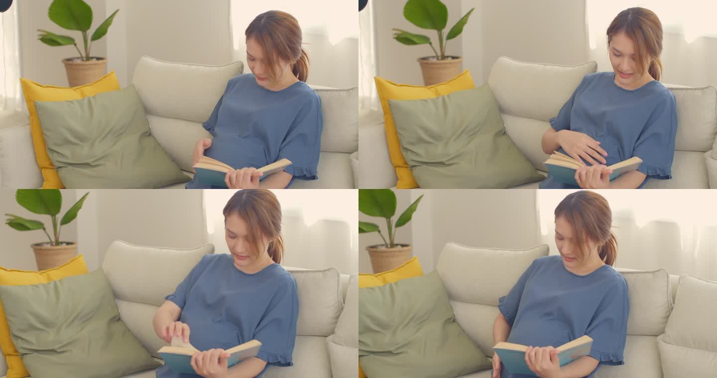 快乐的亚洲孕妇在家看书，轻轻抚摸肚子，怀孕/分娩