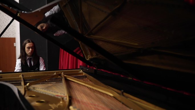 在古典音乐音乐会之前，一位年轻的钢琴家在钢琴上练习奏鸣曲。