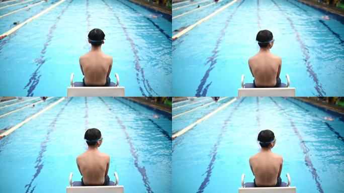 慢动作后视亚裔中国少年坐在游泳池边看