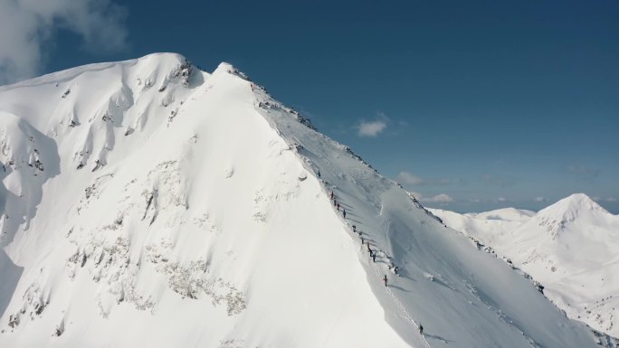 在当地滑雪度假区攀登雪山的滑雪者和单板滑雪者