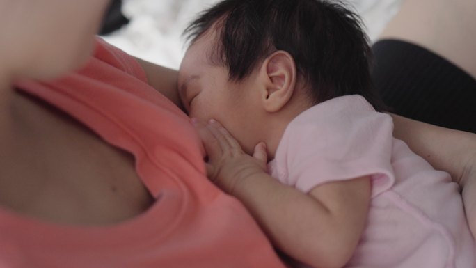 亚洲妇女坐着哺乳她的婴儿